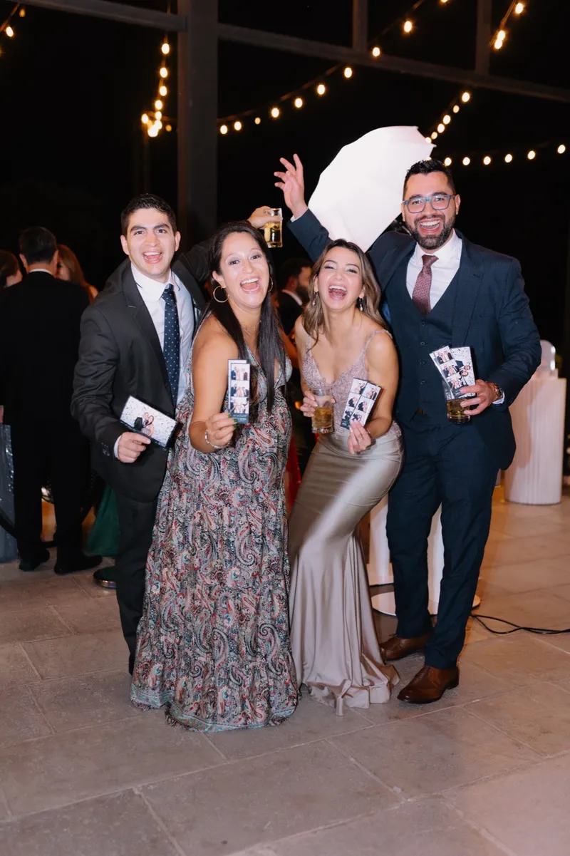 Cuatro invitados riendo con sus tiras de fotos InstaBooth en la mano